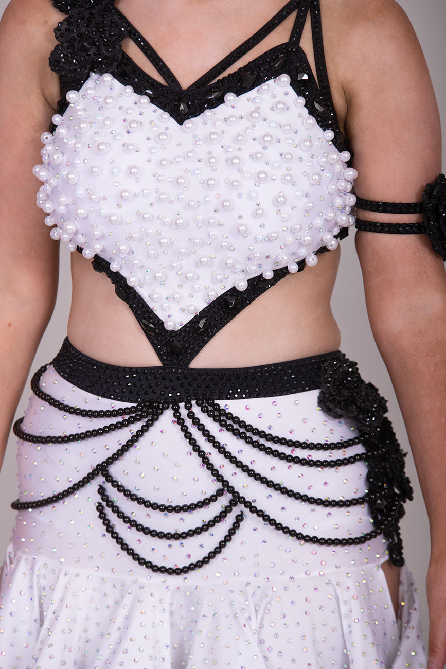 (BUDGET)10 Striking White & Black Competition Latin Dance Dress. Heavily decorated with white pearls & Black bedding all over. Stoned black motif & flower detailing to the hip.