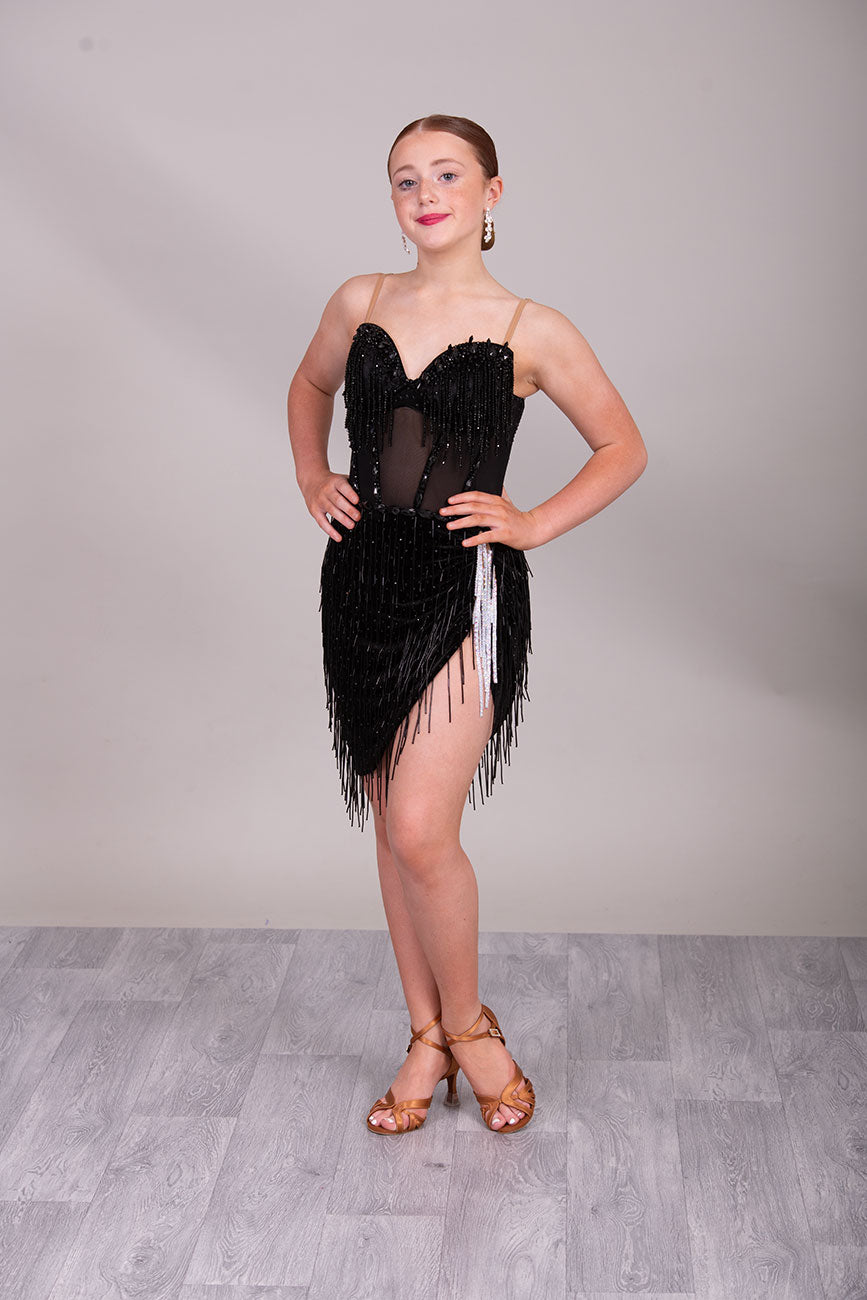 (BUDGET)12 Black Competition Latin Dance Dress. Heavily stoned bodice with beaded tassels. Mesh centre panel with corset details. Asymmetrical skirt stoned & full of beaded tassels. Open back with flesh security straps