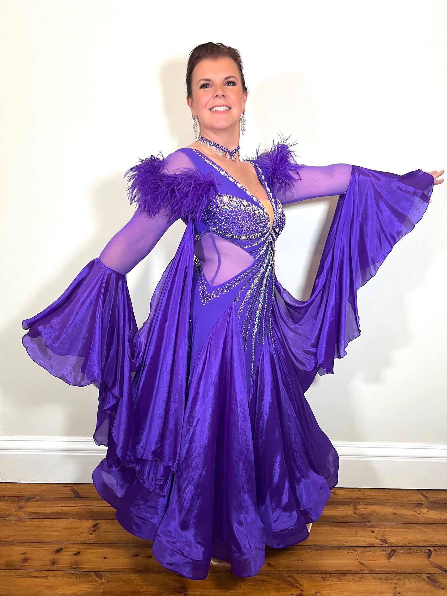 287 Stunning Purple Ballroom Dance Dress. Ostrich feather detail to the upper arm with floaty sleeves from the elbow(finger loop can be added). High back for wearing own bra. Stoned in AB, light Amethyst & Amethyst.