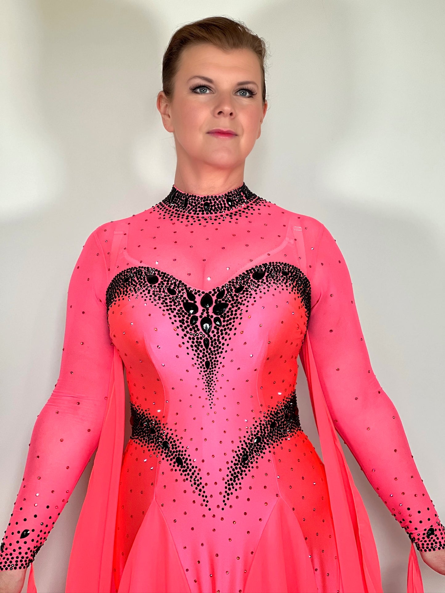 004 Striking Coral Ballroom Dress. Heavily decorated detailing in Jet stones. High back with detachable floats. A stand out eye catching dress.