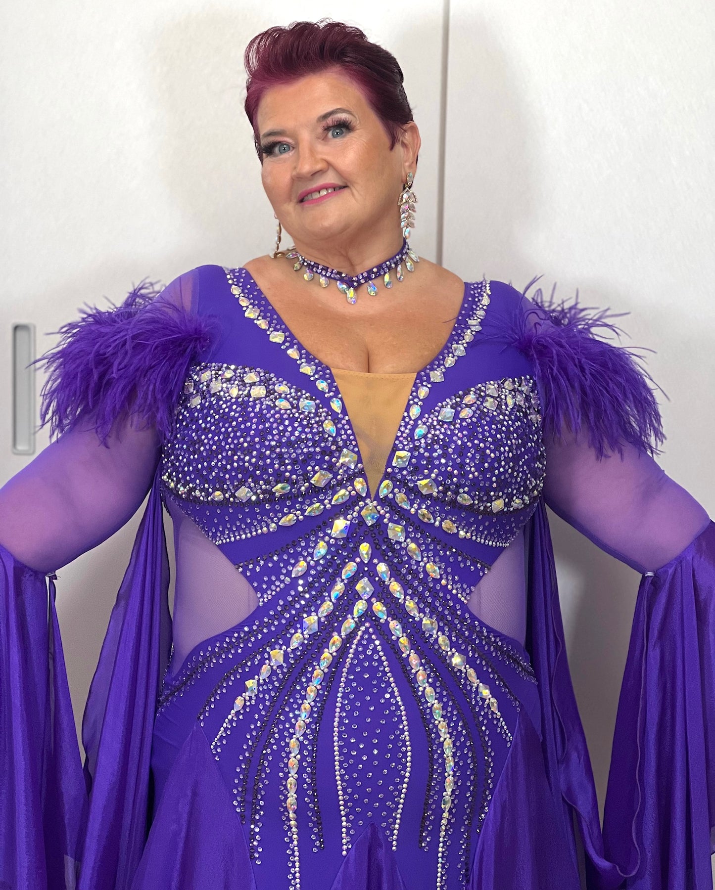 287 Stunning Purple Ballroom Dance Dress. Ostrich feather detail to the upper arm with floaty sleeves from the elbow(finger loop can be added). High back for wearing own bra. Stoned in AB, light Amethyst & Amethyst.