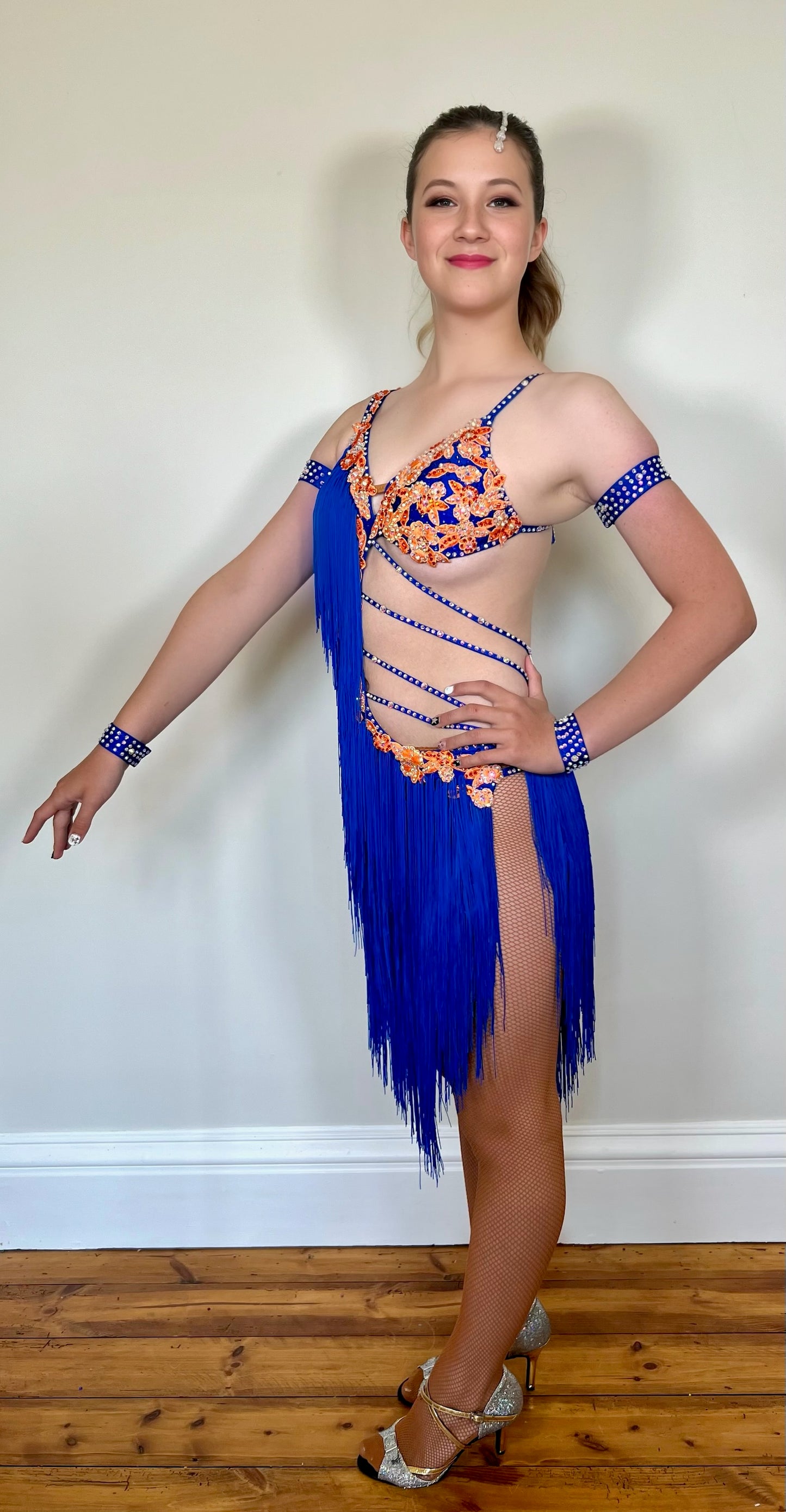108 Bright Royal Blue & Orange strap Detail Latin Dress decorated with orange appliqué AB & sapphire stones. Fringing to the right side and skirt.