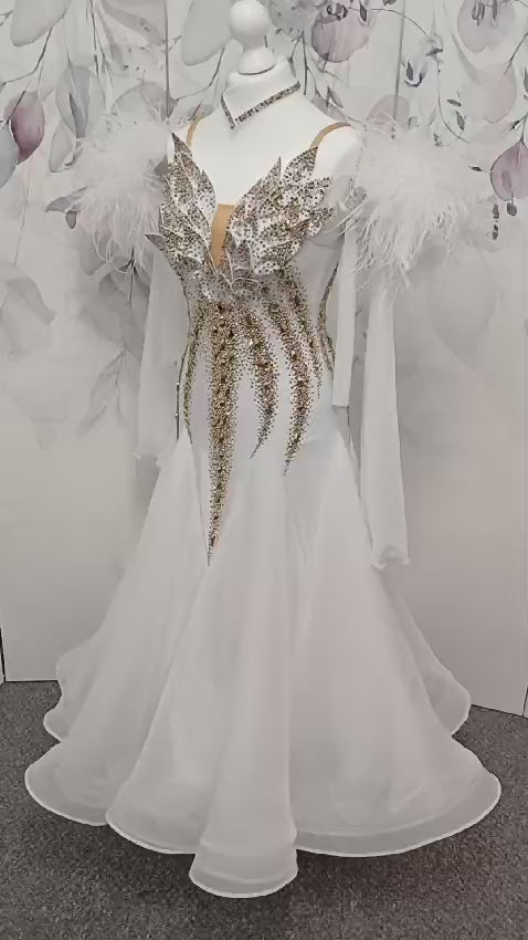 012 Stand out White & Gold Competition Ballroom Dance Dress. 3D design to the Bodice heavily stoned in Gold Ore & Golden Shadow. Detachable Floats with Ostrich feather cuffs.