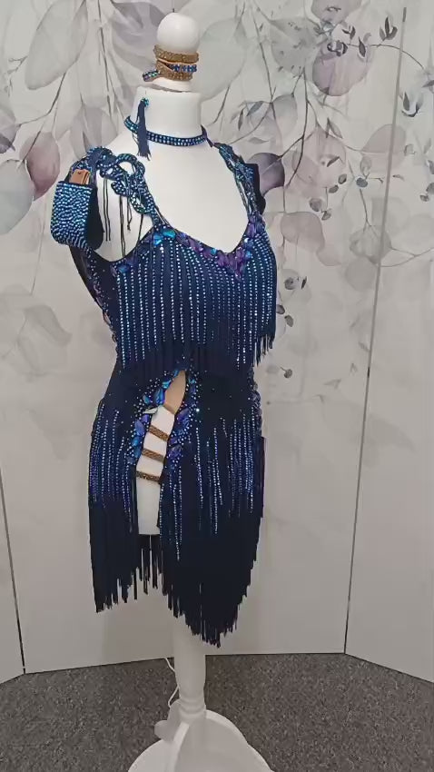 14L Navy Blue Competition Latin/Rhythm Dress. Stoned Fabric Tassels for the Skirt & Upper Chest. Heavily Stoned in Blue AB & Blue. Strappy detailing to the Hips & Drape to the back