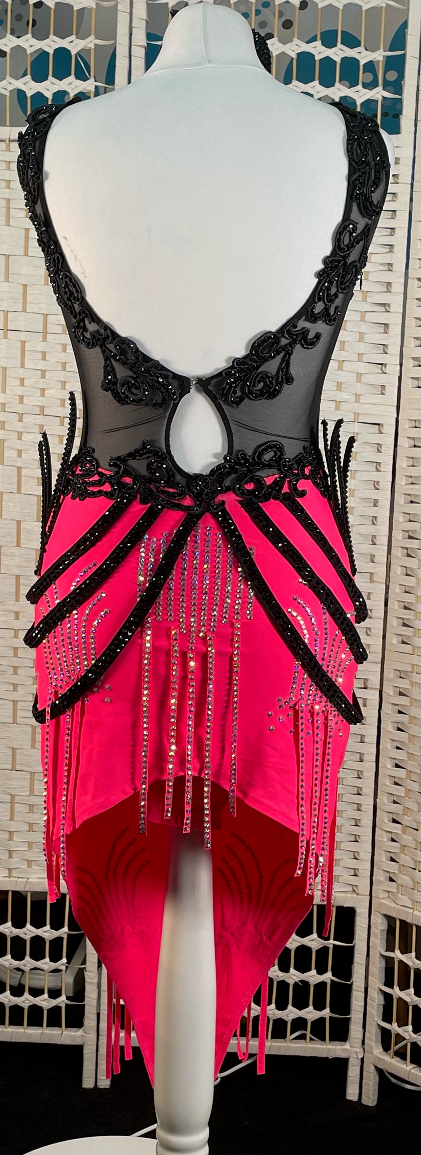 084 Black & Electric Pink Latin Dress. Black mesh bodice decorated with black appliqué & jet stones. Stoned material hip straps. Skirt decorated in AB
